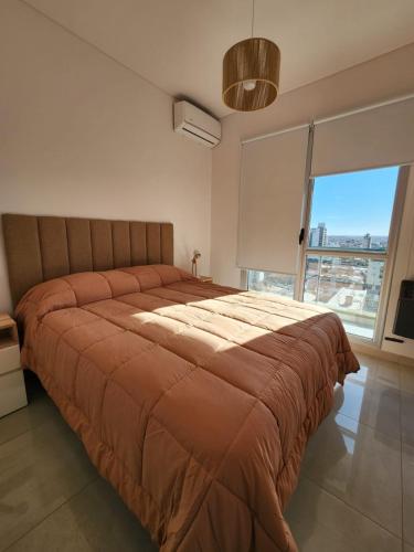 a large bed in a bedroom with a large window at Ohiggins Bahía Premium in Bahía Blanca