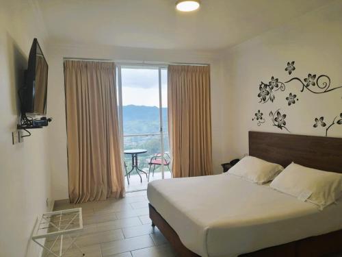 a bedroom with a bed and a balcony with a table at Hotel Entre Lomas in Santa Rosa de Cabal