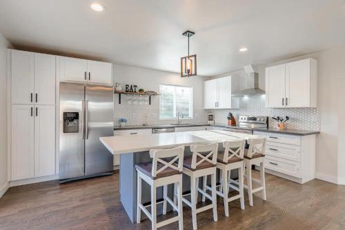 a kitchen with white cabinets and a large island with bar stools at Luxurious 5 Bedroom Home with AC and EV Plug in Seattle