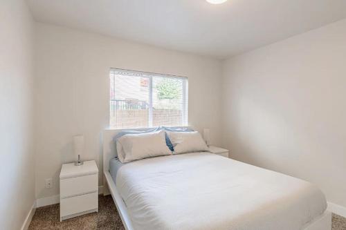 a white bedroom with a bed and a window at Luxurious 5 Bedroom Home with AC and EV Plug in Seattle