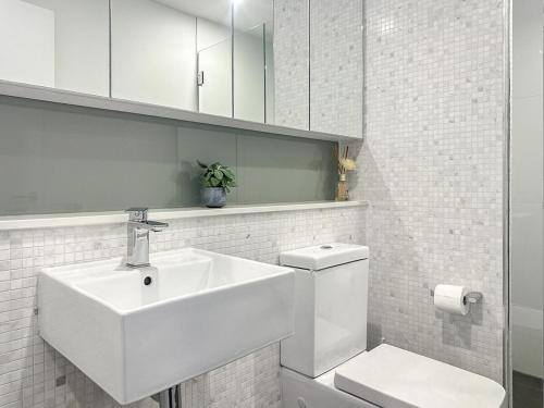 a white bathroom with a sink and a toilet at Stylish 1BR1BA apt in Footscray Pool Gym WIFI in Melbourne