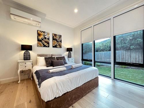 a bedroom with a large bed and large windows at Luxury Glen Waverley Townhouse 4br3ba Backyard in Glen Waverley