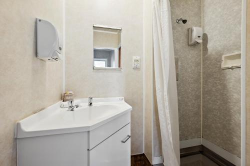 a bathroom with a white sink and a shower at Flamingo Motel in New Plymouth