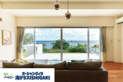 a living room with a couch and a view of the ocean at オーシャンヴィラ 海テラス Ishigaki in Ishigaki Island