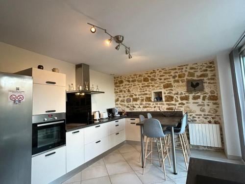 - une cuisine avec des placards blancs et un mur en pierre dans l'établissement Maison berrichonne authentique avec jardin, près du Domaine de George Sand et activités variées - FR-1-591-195, à Nohant-Vic