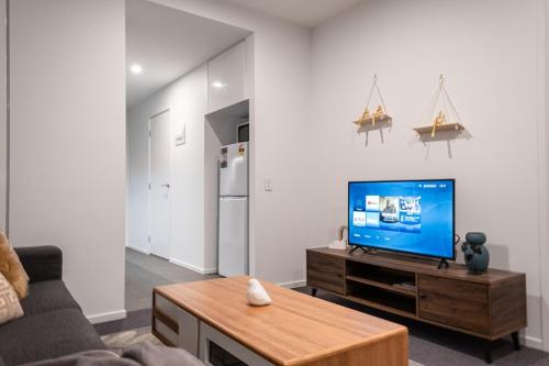 a living room with a television on a wooden table at Footscray pool pleasant &Bright 2BR2BA apt in Melbourne