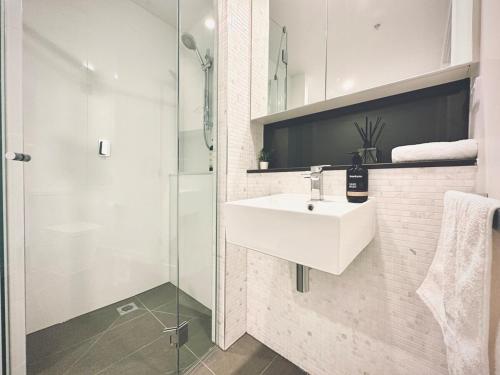 a white bathroom with a sink and a shower at Footscray pool pleasant &Bright 2BR2BA apt in Melbourne