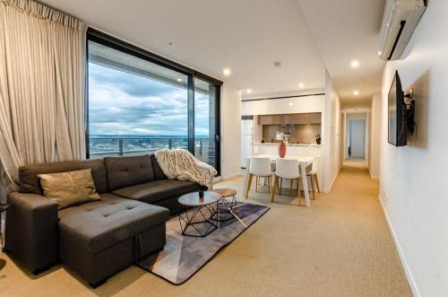 a living room with a couch and a table and a kitchen at Luxury living on top floors 3 Bedroom Mel CBD Pool in Melbourne