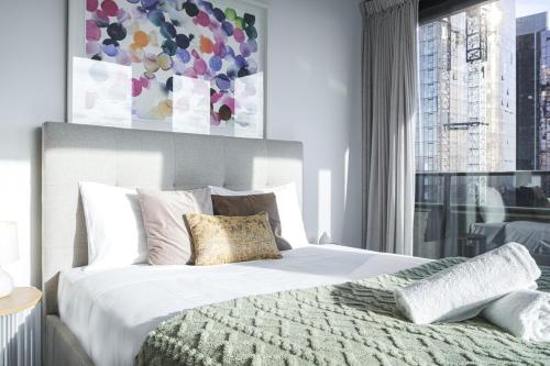 a bedroom with a white bed with a large window at Luxury living on top floors 3 Bedroom Mel CBD Pool in Melbourne