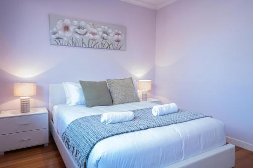 a white bedroom with a bed with two lamps at Nunawading Beautiful 3br Housedeckingcourtyard in Nunawading