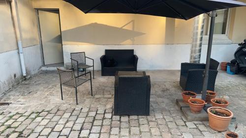 un patio avec une table, des chaises et un parasol dans l'établissement Studio à 2 arrêt de Gare du Nord, à Pierrefitte-sur-Seine