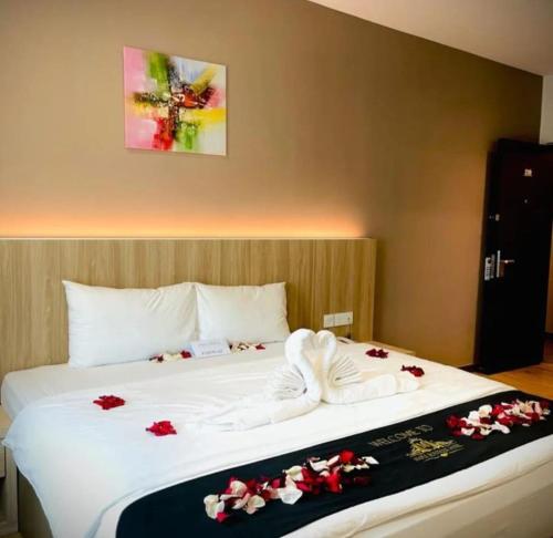 a bed with white sheets and red flowers on it at Maple Boutique Hotel in Melaka