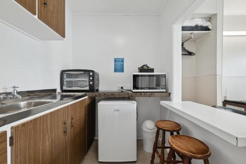 a small kitchen with a sink and a refrigerator at Flamingo Motel in New Plymouth