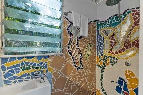 a bathroom with a shower with a mosaic shower curtain at Garden Burees in Byron Bay