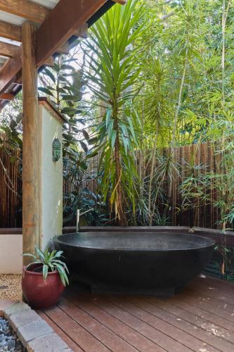 a black bath tub sitting on a wooden deck at Garden Burees in Byron Bay
