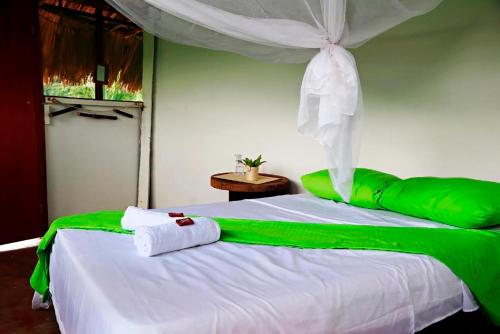 a bedroom with a bed with green and white sheets at HOSTAL MIRADOR dentro del parque tayrona in El Zaino