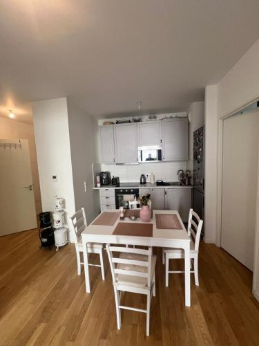 - une cuisine avec une table et des chaises blanches dans la chambre dans l'établissement Appartement T3 Haut de standing paris, à Clichy