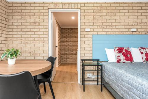 a room with a bed and a table and a brick wall at Lismore Wilson Motel in Lismore