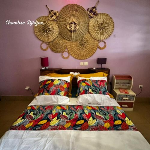 a bedroom with a bed with hats on the wall at Les Chambres D'À Côté in Lomé
