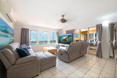 a living room with a couch and a tv at Martinique Whitsunday Resort in Airlie Beach