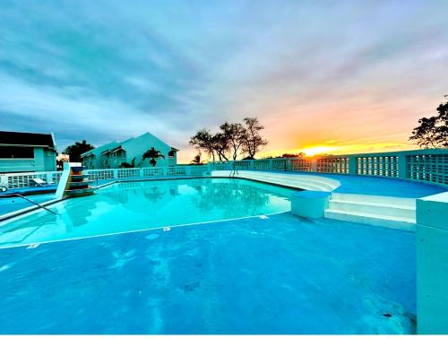 a large swimming pool with a sunset in the background at Casa Mire-Lee, Seaside Serenity at Negril 7 miles Beach, Point Village in Negril
