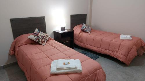 a room with two beds with red blankets and a table at Departamentos Centro in Belén