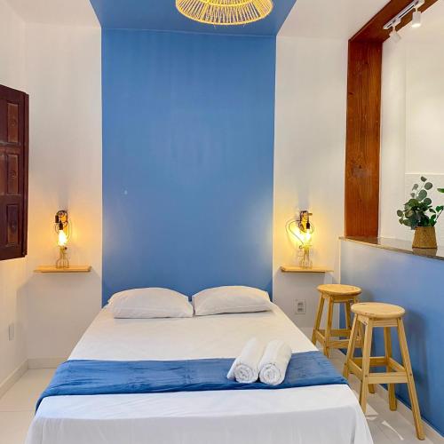 Un dormitorio con paredes azules y una cama con dos taburetes. en Morada da Lena - Praia do Forte, en Farol