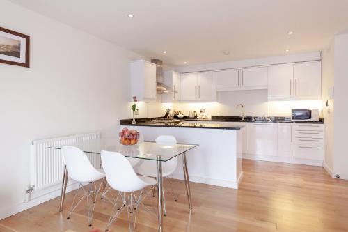 エプソムにあるRoomspace Serviced Apartments - Marquis Courtの白いキャビネットとテーブルと椅子のあるキッチン