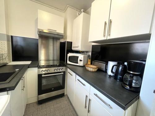 une cuisine avec des armoires blanches et un four à plaques de cuisson dans l'établissement Charmant F2 à Banyuls-sur-Mer - Proche plage avec parking privatif - FR-1-309-166, à Banyuls-sur-Mer