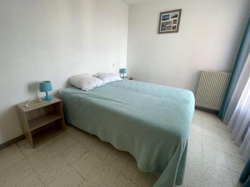 - une chambre avec un lit doté d'une couverture bleue dans l'établissement Charmant F2 à Banyuls-sur-Mer - Proche plage avec parking privatif - FR-1-309-166, à Banyuls-sur-Mer