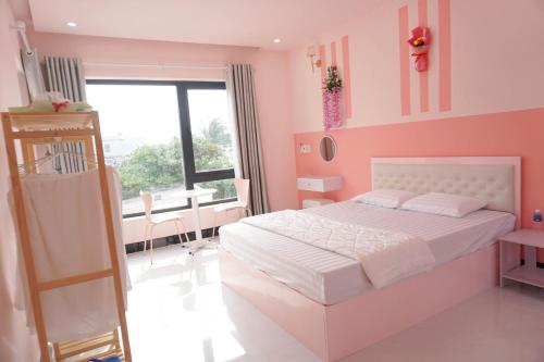 a pink bedroom with a white bed and a table at Pink Sea Villa in Cu Lao Thu