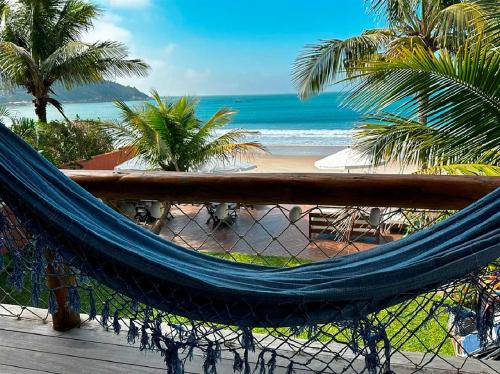 a hammock on a balcony overlooking a beach at Pousada Pedra da Gaivota in Bombinhas