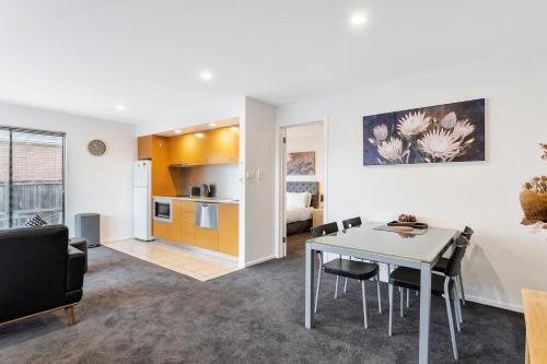 a living room and kitchen with a table and chairs at Four on Flinders - one bedroom apartment in Sandy Bay