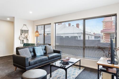 a living room with a leather couch and a large window at Four on Flinders - one bedroom apartment in Sandy Bay