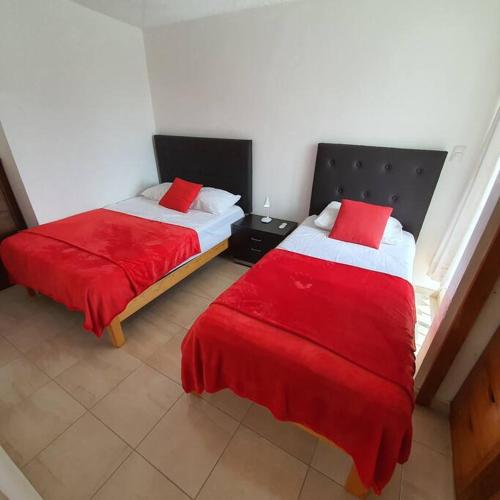 two beds in a room with red sheets at Departamento centrico - con todos los servicios - Facturamos in Durango