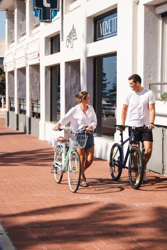 a man and a woman riding bikes down a street at Cottesloe Beach Hotel in Perth