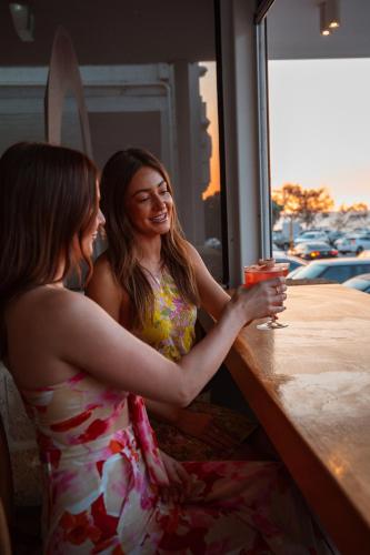 two women sitting at a table with a drink at Cottesloe Beach Hotel in Perth