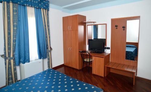 a bedroom with a bed and a desk with a television at Hotel La Cantina in Alfonsine