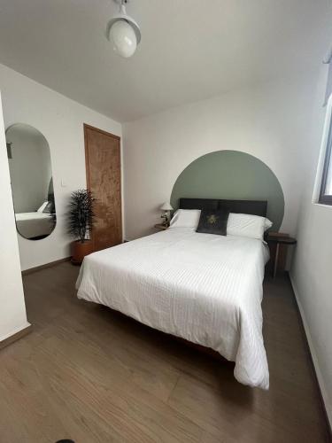 a bedroom with a large white bed with a green headboard at Am Cinco Condesa in Mexico City