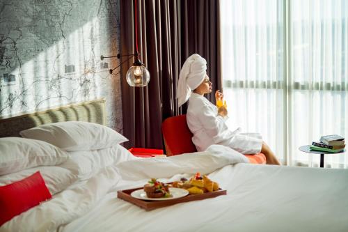 a woman in a suite with a tray of food on a bed at IntercityHotel Nizwa in Nizwa