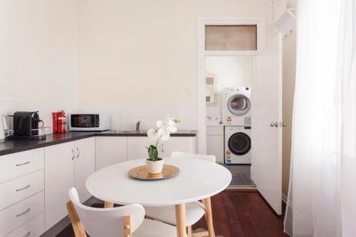 a white kitchen with a white table and chairs at Rosa's Place 3 Sth Beach Villa in South Fremantle