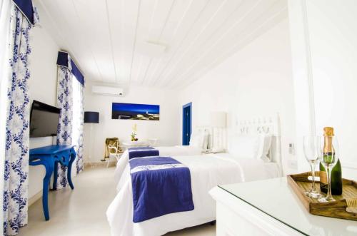 a white bedroom with a bed and a table at Hotel Solar do Arco in Cabo Frio