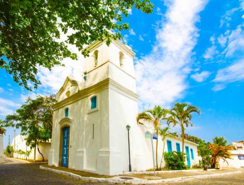 a white building with a clock tower on a street at Hotel Solar do Arco in Cabo Frio