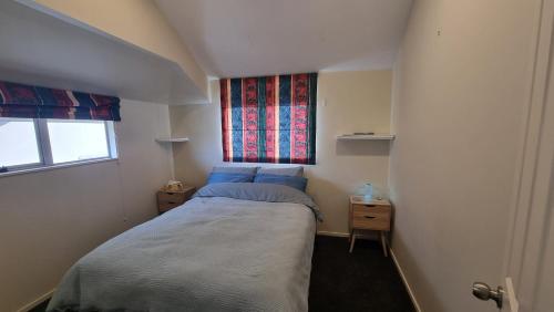 a small bedroom with a bed and a window at Home stay - Double Bed at Churton Park in Wellington