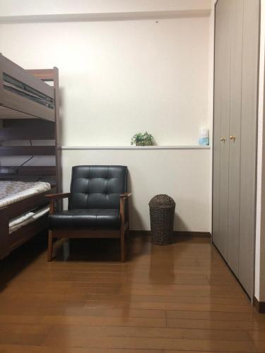 a bedroom with a black chair and a bed at kotobuki504condotel in Imai-kamichō