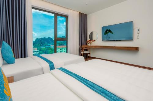 Una habitación de hotel con dos camas y un televisor de pantalla plana. en River Way Hotel Ha Long, en Ha Long