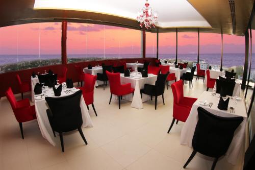 a restaurant with white tables and red chairs at Anarva Hotel & Spa in Mount Lavinia