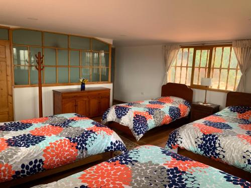 a room with three beds with colorful blankets at Casa Laurel in Monguí