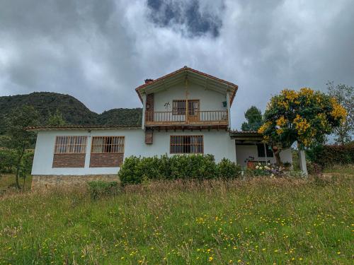 a white house with a balcony on top of a field at Casa Laurel in Monguí