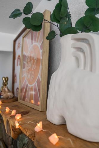 a white vase with a plant in it next to a picture at Rosequartzplayhouse Wgmrm&more! in Sedona